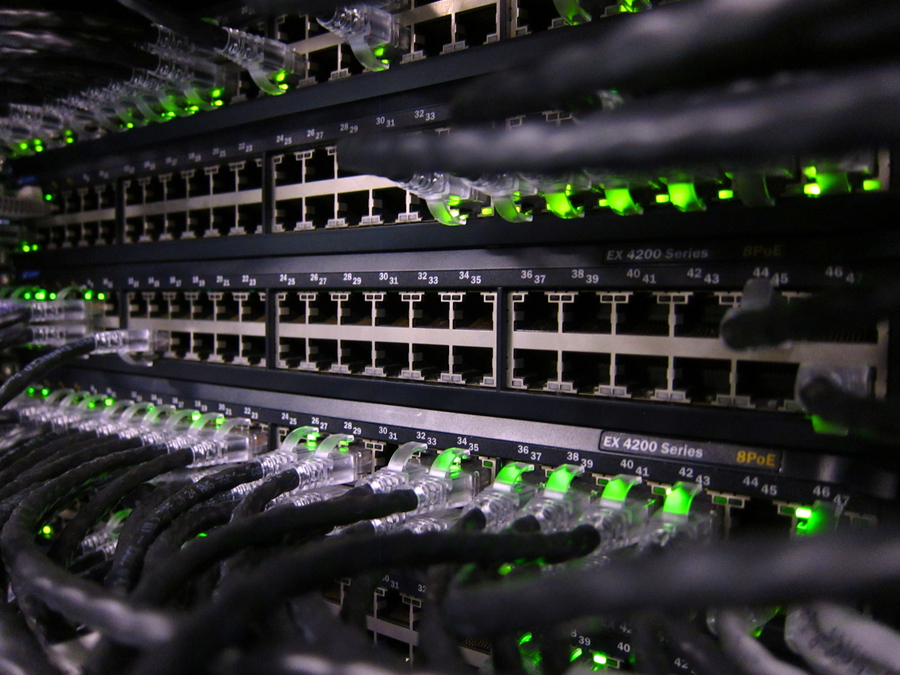 Close-up of network switches with Ethernet cables and green status lights in a professional networking rack.