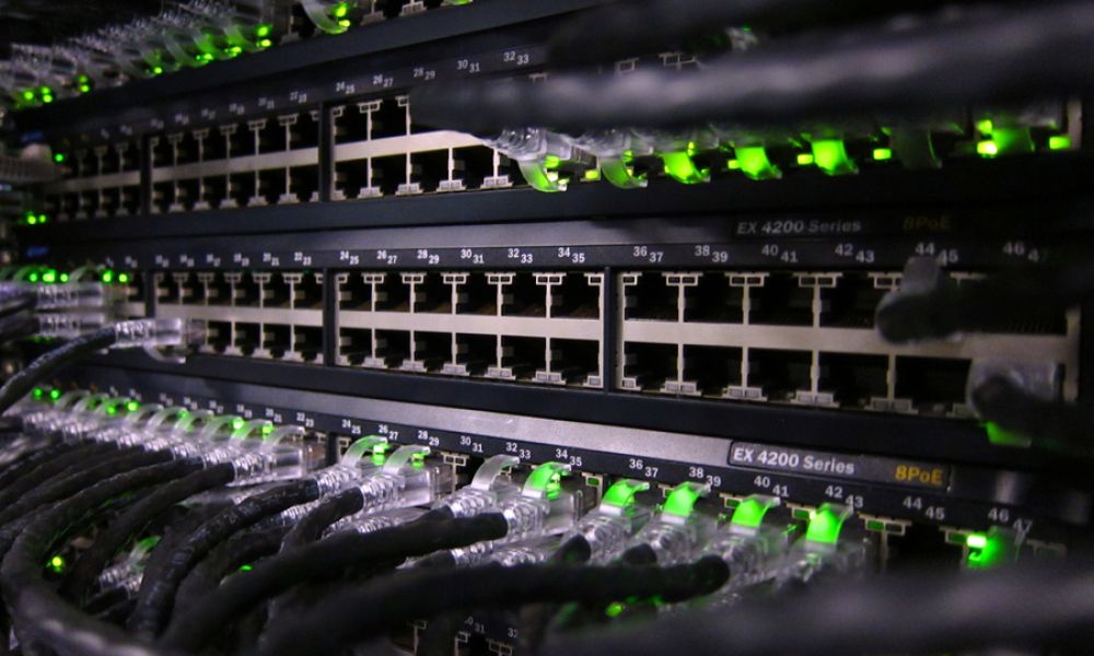 Close-up of network switches with Ethernet cables and green status lights in a professional networking rack.