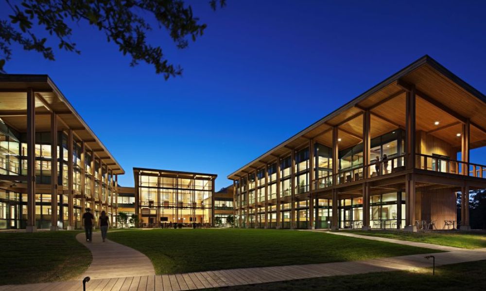 A large, well-lit commercial building with people walking along its perimeter.