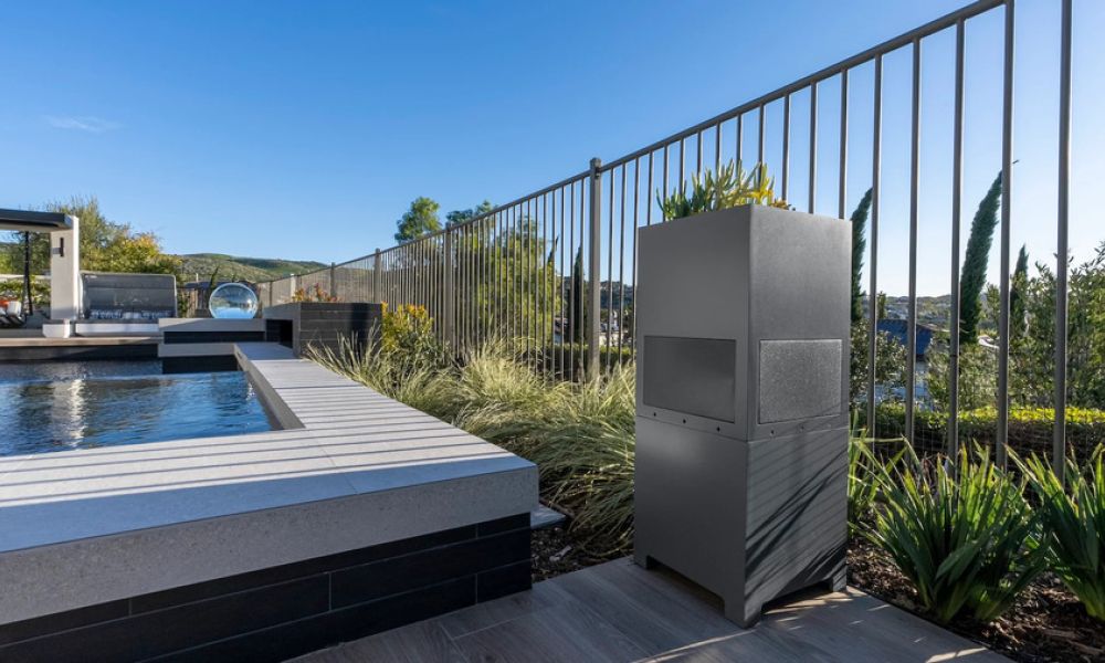 Outdoor landscape speaker installed beside a modern pool and patio, blending into the landscape.