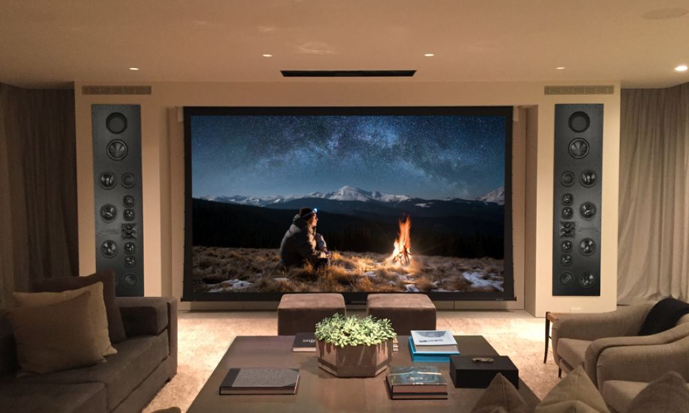 A media room with a large screen surrounded by James Loudspeakers.