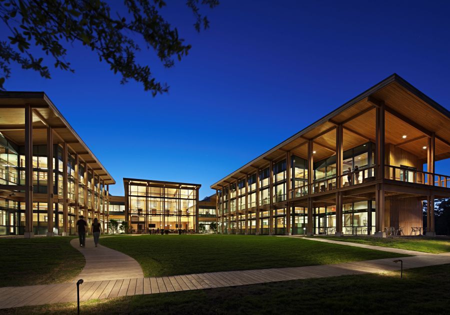 A large, well-lit commercial building with people walking along its perimeter.